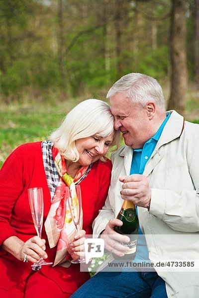 älteres Paar öffnen Weinflasche im park
