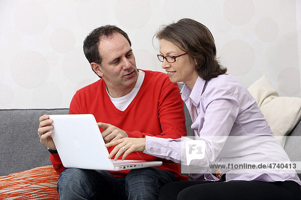 Paar  Mann  Frau  Mitte 40  zuhause beim Surfen im Internet am Laptop
