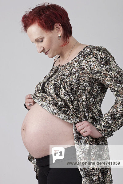 Schwangere Frau blickt auf Babybauch