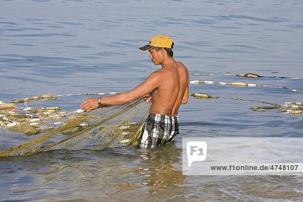 Ein Fischer holt sein ausgelegtes Netz mit dem Fischfang aus dem Meer herein  Insel Phu Quoc  Vietnam  Südostasien