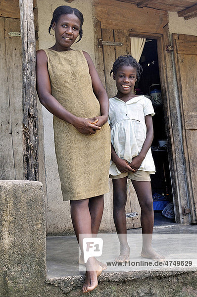 Mutter und Tochter vor ihrem einfachen Haus aus Holz  Petit Goave  Haiti  Karibik  Zentralamerika Holzhaus
