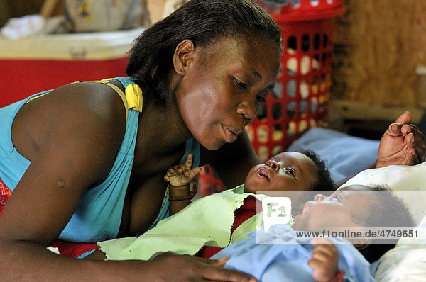 Mutter Rosita Thomas  31  mit ihren Zwillingen Mickenson und Tickenson  3 Monate  in einem erbebensicheren Fertighaus  das der Familie von einer Hilfsorganistion zur Verfügung gestellt wurde  Petit Goave  Haiti  Karibik  Zentralamerika