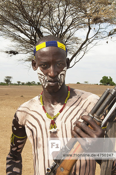 Karo warrior with body and facial paintings holding a rifle  Omo river valley  Southern Ethiopia  Africa