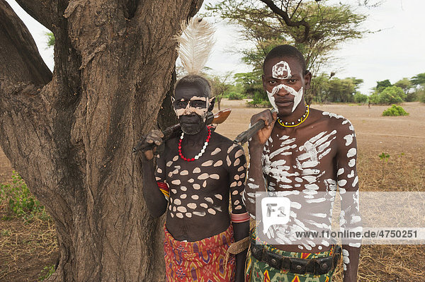 Two Karo warriors with body and facial paintings holding a rifle over their shoulder  Omo river valley  Southern Ethiopia  Africa