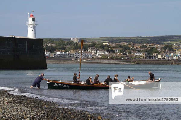 Cornish pilot gig rowing boat entering the water  Newlyn  Cornwall  England  United Kingdom  Europe