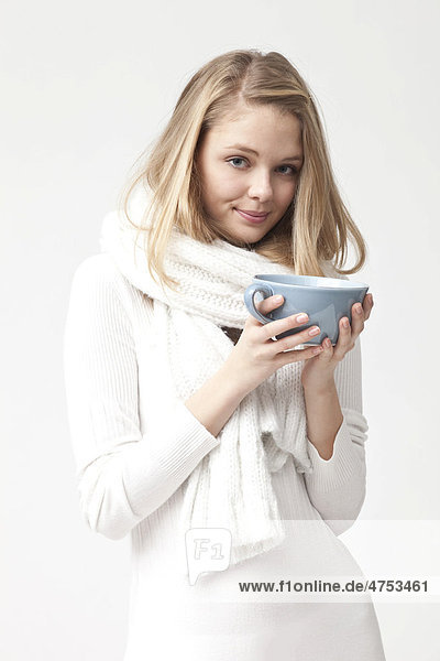 Weißgekleidete junge Frau hält Teetasse