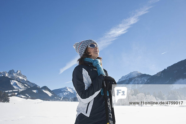 Smiling woman with nordic walking poles in winter landscape  Tannheimer Tal  Tyrol  Austria