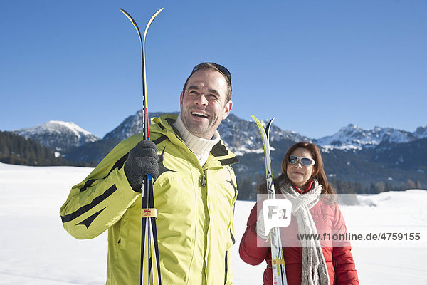 Lächelndes Paar mit Skiern in Winterlandschaft  Tannheimer Tal  Tirol  Österreich