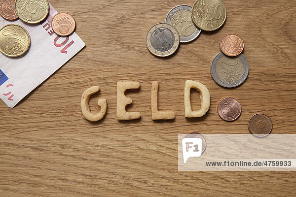 Geld  German for money  word written with biscuits  beside coins and a banknote