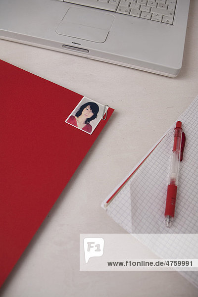 Job application file with photo beside a laptop