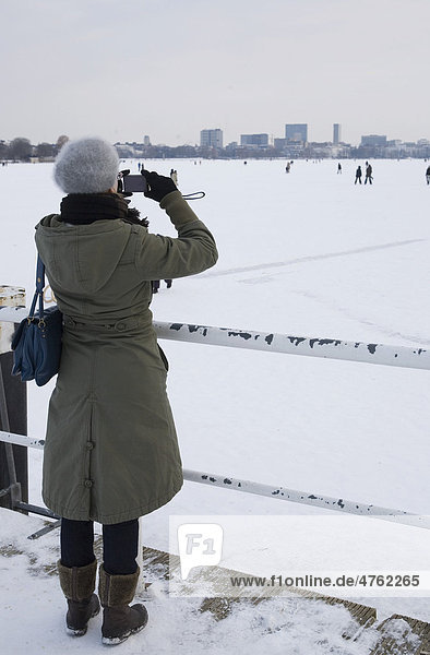 Junge Frau fotografiert die zugefrorene Alster  Hamburg  Deutschland  Europa