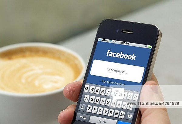 Man logging in into his Facebook account on his iPhone 4