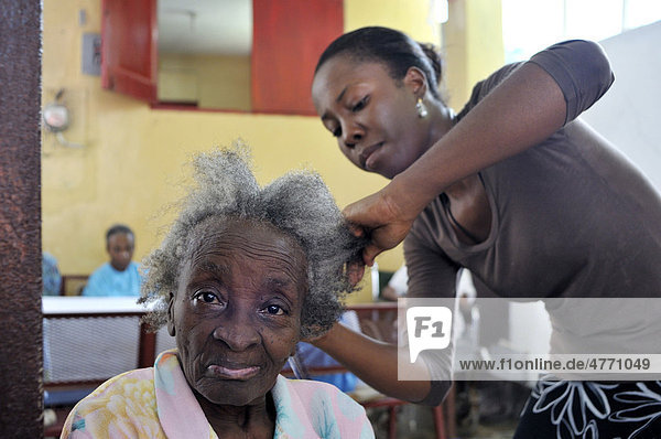 Junge Frau  freiwillige Helferin  frisiert eine Seniorin in einem Altenheim  Stadtteil Turgeau  Port-au-Prince  Haiti  Karibik  Zentralamerika