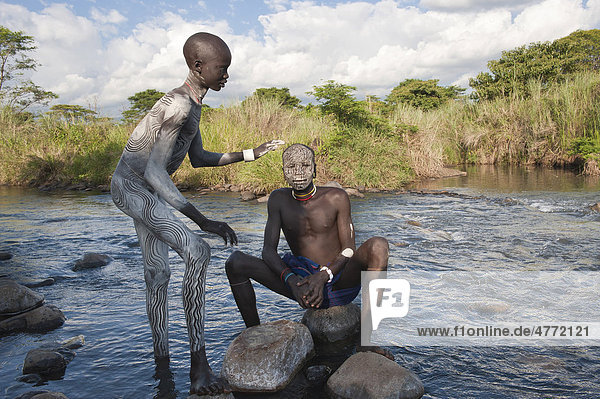 Zwei Surma Männer mit Gesichtsbemalung und Körperbemalung im Wasser  Kibish  Omo-Tal  Äthiopien  Afrika