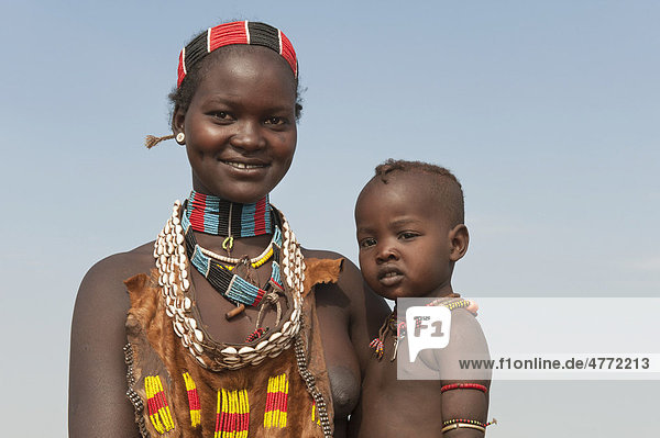 Junge Hamar Frau mit Halskette aus Kaurimuscheln und bunten Plastikperlen hält ihr Baby im Arm  Omo-Tal  Süd Äthiopien  Afrika