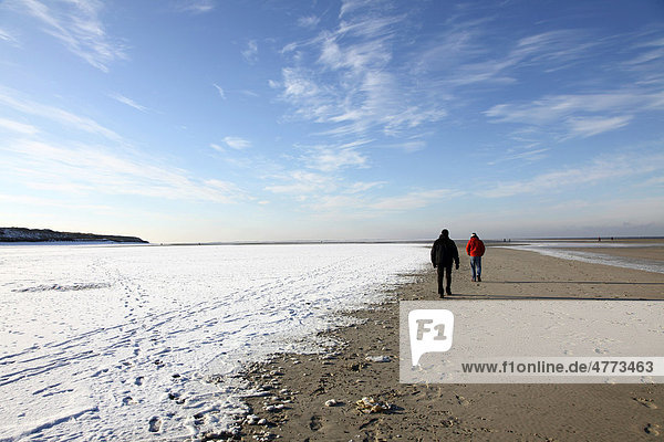 People walking along the snow-covered beach on the East Frisian North Sea island of Spiekeroog  Lower Saxony  Germany  Europe
