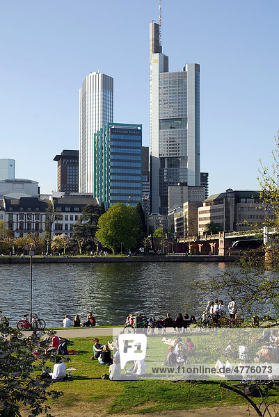 Leute am Mainufer  Schaumain Kai  Museumsufer  dahinter die Skyline vom Büro- und Bankenviertel  Frankfurt am Main  Hessen  Deutschland  Europa