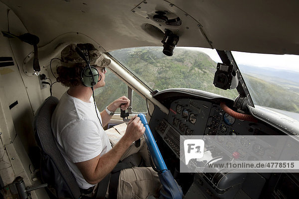 Pilot in cockpit of bush plane  float plane de Havilland Canada DHC-3 Otter  Yukon Territory  Canada