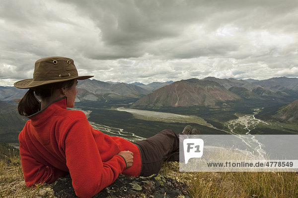 Junge Frau rastet und genießt die Aussicht  Wind River Valley  nördliche Mackenzie Mountains Gebirgskette  Yukon Territorium  Kanada
