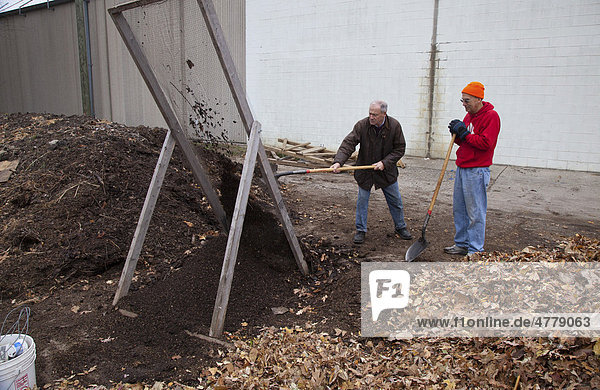 Zwei Männer schaufeln Kompost durch ein Kompostgitter auf der Earthworks Urban Farm  einem Gärtnerei-Programm der Capuchin Soup Kitchen Suppenküche  Detroit  Michigan  USA