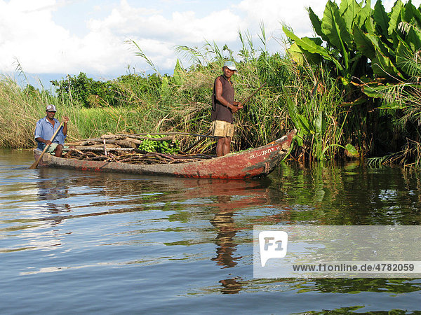 Männer in einem Kanu  beladen mit Brennholz  Zuckerrohr und Bananen  Madagaskar  Afrika