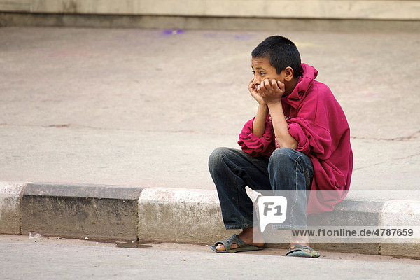 Straßenkind blickt mit Kopf auf Hände gestützt traurig in Ferne  Pokhara  Nepal  Asien