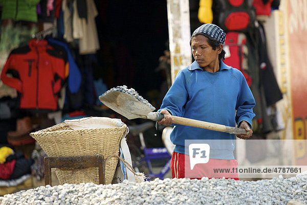 Bauarbeiter schaufelt Kies in Tragekorb  Pokhara  Nepal  Asien