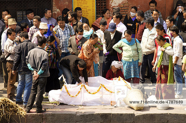 Mutter im traditionellen Gewand und andere Teilnehmer eines Begräbnis umstehen zur Verbrennung aufgebahrte Leiche eines Verwandten und nehmen Abschied  Pashupatinath  Nepal  Asien