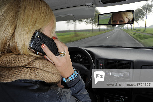 Junge Frau telefoniert beim Autofahren