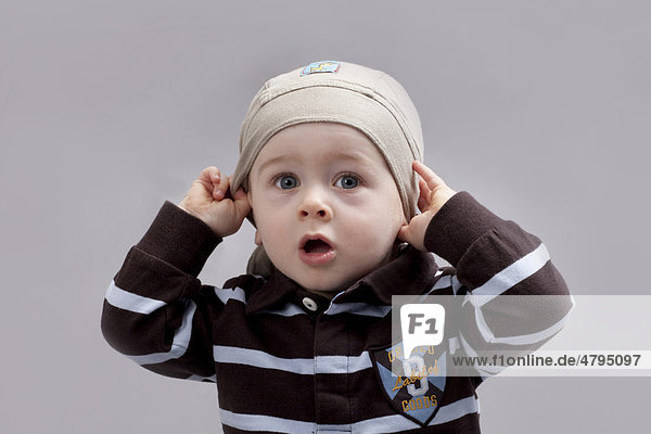 Baby zieht sich Mütze ins Gesicht  Junge  8 Monate  Porträt