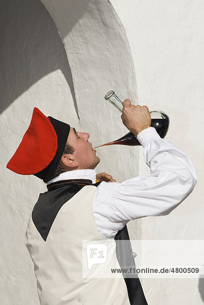 Junger Mann in traditioneller Tracht trinkt Wein aus einem typisch spanischen Porron  Ibiza  Spanien  Europa