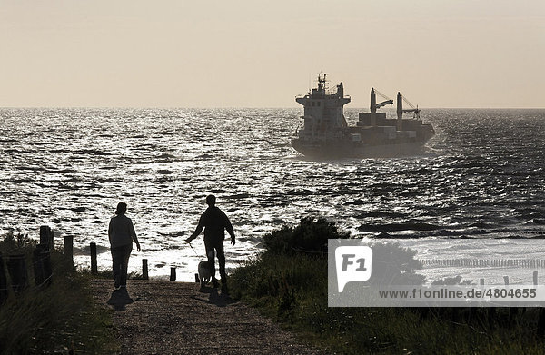 Pärchen wandert durch die Dünen  Frachtschiff auf dem Meer  Gegenlicht  Zoutelande  Walcheren  Provinz Zeeland  Niederlande  Benelux  Europa