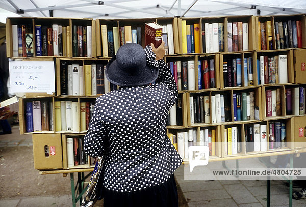 Ältere Frau nimmt dicken Roman aus einem Verkaufsregal  Open-Air-Büchermarkt auf der Königsalle  Kö  Düsseldorf  Nordrhein-Westfalen  Deutschland  Europa