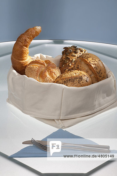 Bread basket on a glass table with napkin  knife and fork