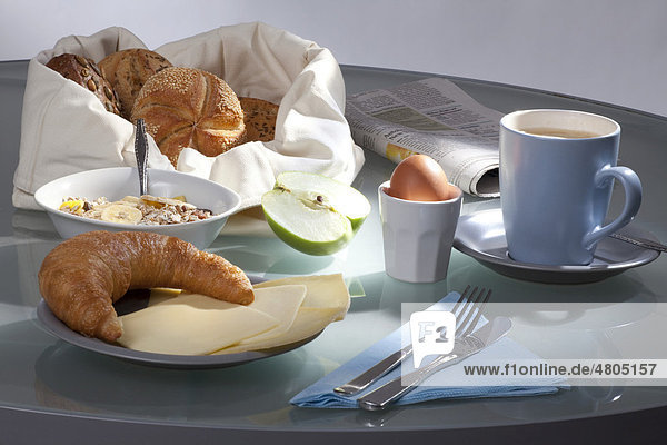 Gedeckter Frühstückstisch mit Kaffee, Brötchen, Müsli, Käse, Apfel ...