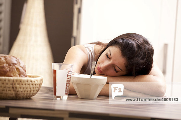 Young woman sitting at a dining table  sleeping