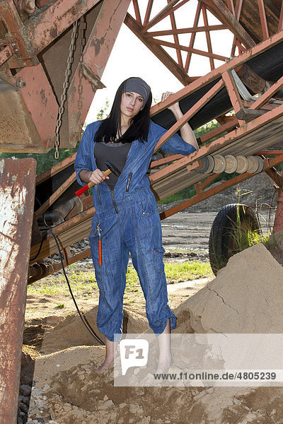 Junge Frau im Jeansoverall mit Werkzeug