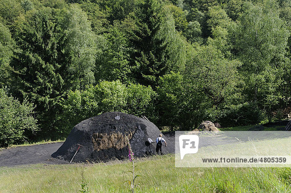 Ein neuer Holzkohlenmeiler wird mit Grassoden abgedeckt und mit Kohlerde abgedichtet Walpersdorf Kreis Siegen-Wittgenstein Nordrhein-Westfalen Deutschland