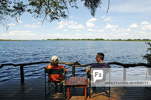 Tourists sitting on the terrace of a lodge on the Guma Lagoon  Okavango Delta  Botswana  Africa