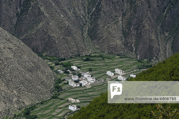 Blick von oben auf die tibetische Architektur eines kleinen Dorfes  Häuser inmitten eines steilen Canyons mit Feldterrassen zum Anbau  Xiangcheng  Chaktreng  Kham  Sichuan  China  Asien