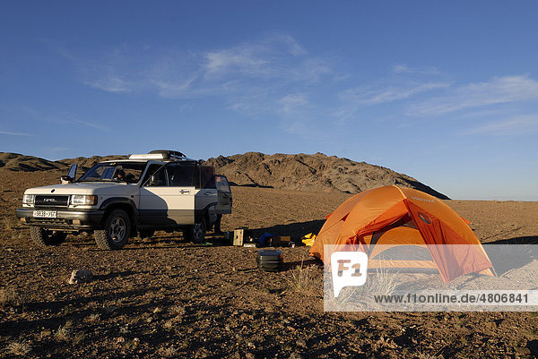 Weißer Opel Landcruiser steht mit offenen Türen neben Zeltlager mit Trekkingzelt und Outdoor Equipment in der Wüste Gobi  Khorgoryn Els  Gurvan Saikhan Nationalpark  Ömnögov Aimak  Mongolei  Asien