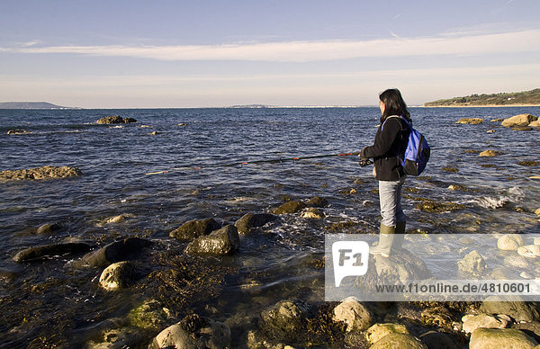 Woman angelt im Meer am Rocky Beach Strand  Jurassic Coast  Ringstead Bay  Dorset  England  Großbritannien  Europa
