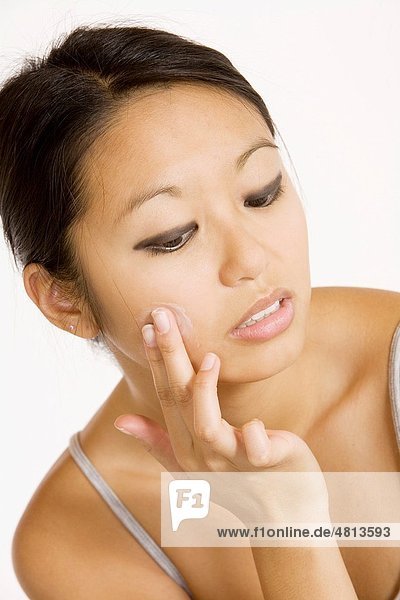 Young Asian woman applying moisturizing cream on her face