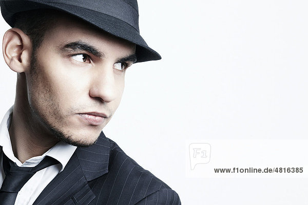 Seitliches Portrait eines jungen Mannes mit Anzug  Hemd  Krawatte und Hut