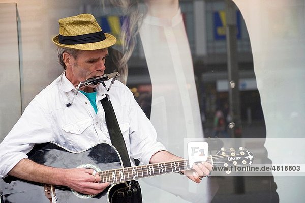 A guitarplayer is making music in front of a shop