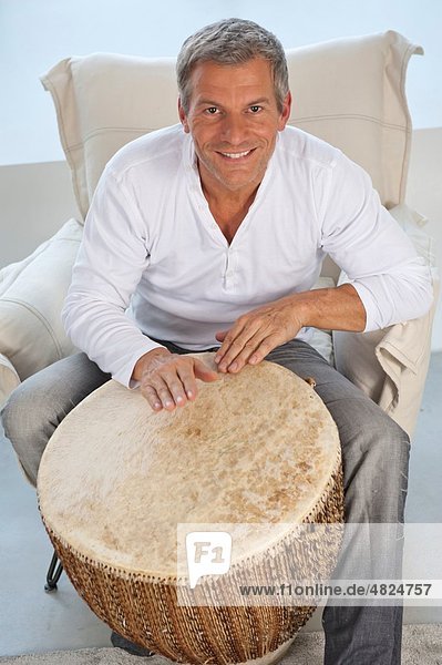 Erwachsener Mann spielt zu Hause Trommel  lächelnd  Portrait