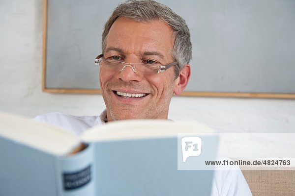 Reifer Mann liest Buch  lächelnd