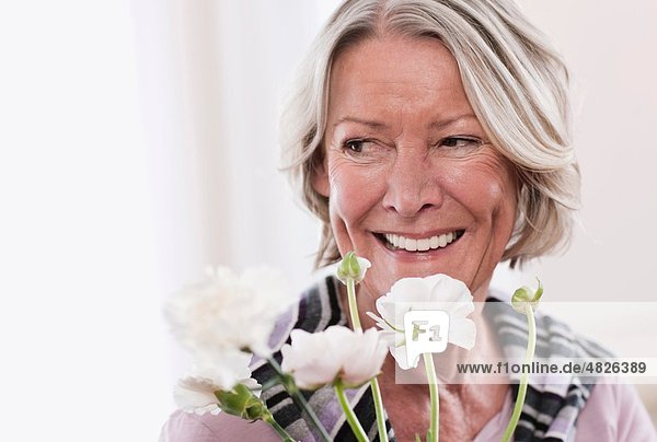 Seniorin mit Blumen  lächelnd