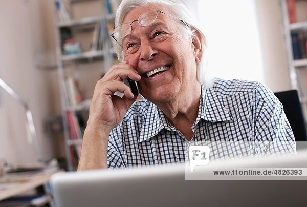 Senior man on the phone with laptop  smiling