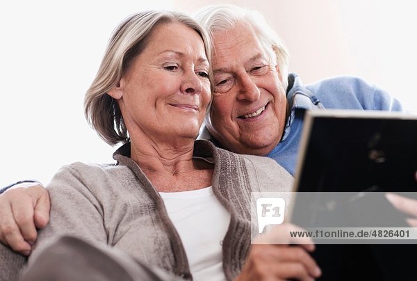 Deutschland  Wakendorf  Seniorenpaar beim Betrachten des Bilderrahmens  lächelnd